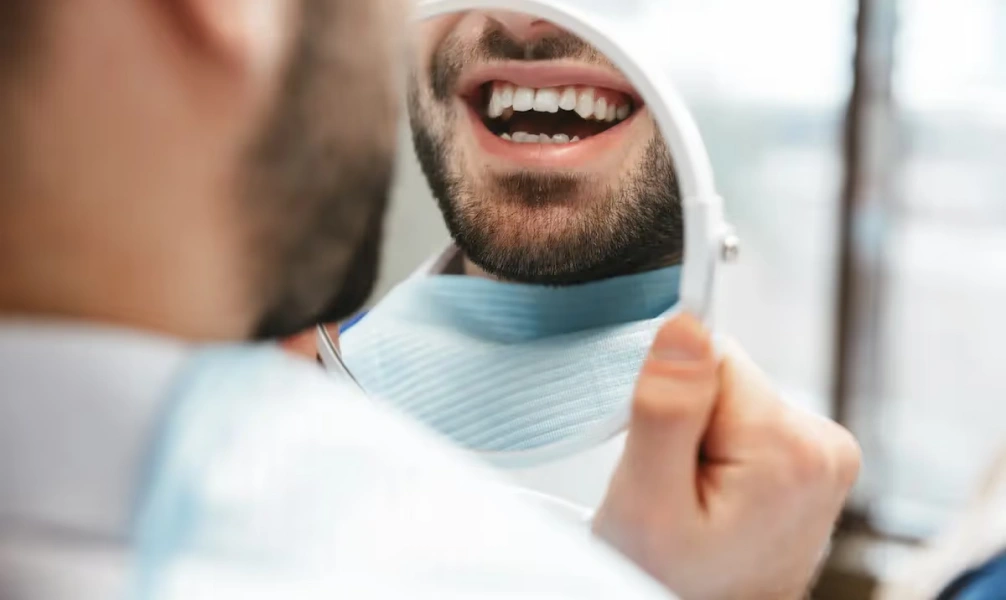 Man smiling while checking his teeth after a dental filling